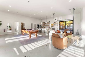 A spacious living area with a pool table, seating, and a large window. - Modern Home w/ Hot Tub & Backyard Oasis! (Sevierville)