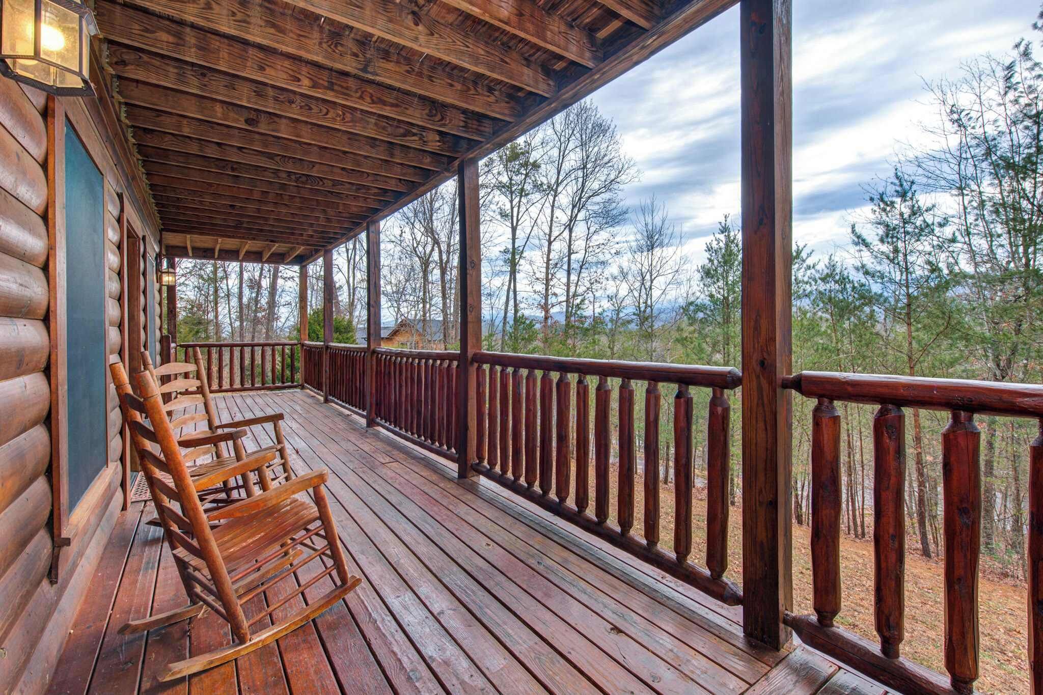 A wooden deck with a railing, overlooking a forested area.