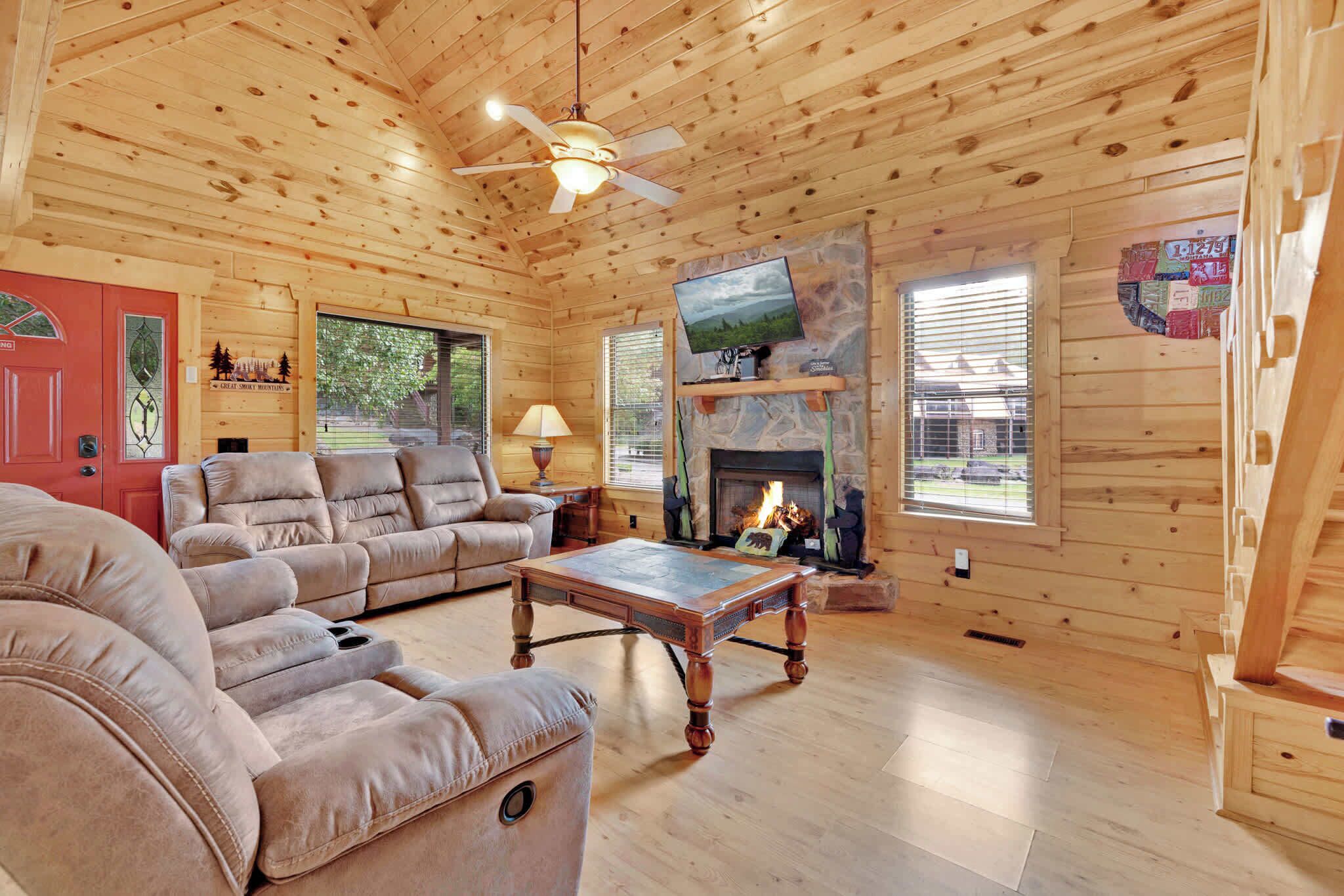Ein Holzinterieur mit einer Couch, einem Tisch, einem Kamin und einem Fernseher.