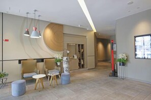 Un área de recepción moderna con un sofá, sillas, una mesita y una pared decorativa.