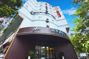 Un hotel con fachada curva, señalización en varios idiomas y un cielo despejado al fondo.