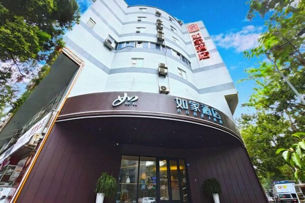 A hotel with a curved facade, signage in multiple languages, and a clear sky in the background.