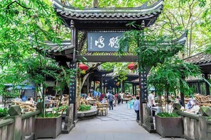 A traditional Chinese pavilion with a sign, surrounded by bamboo plants and outdoor seating areas.