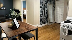 Eine moderne Küche mit einem Holztisch, einem weißen Herd und einer Tür mit tropischem Blattmuster.