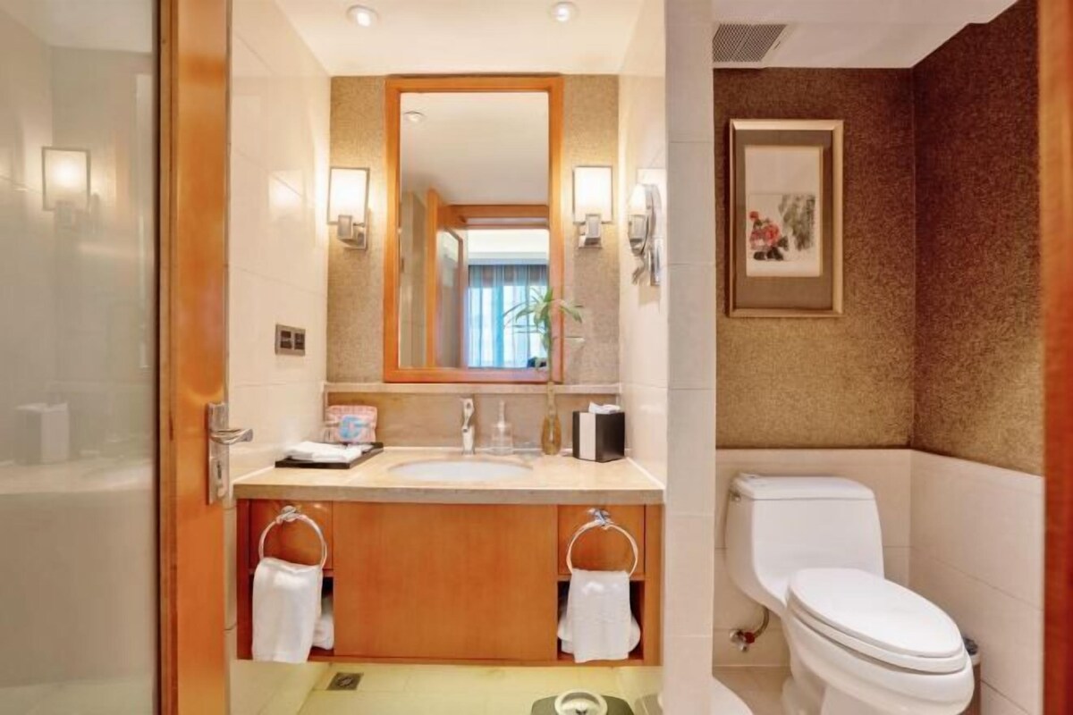 A modern bathroom with a glass shower enclosure, a wooden vanity with a sink, and a toilet.