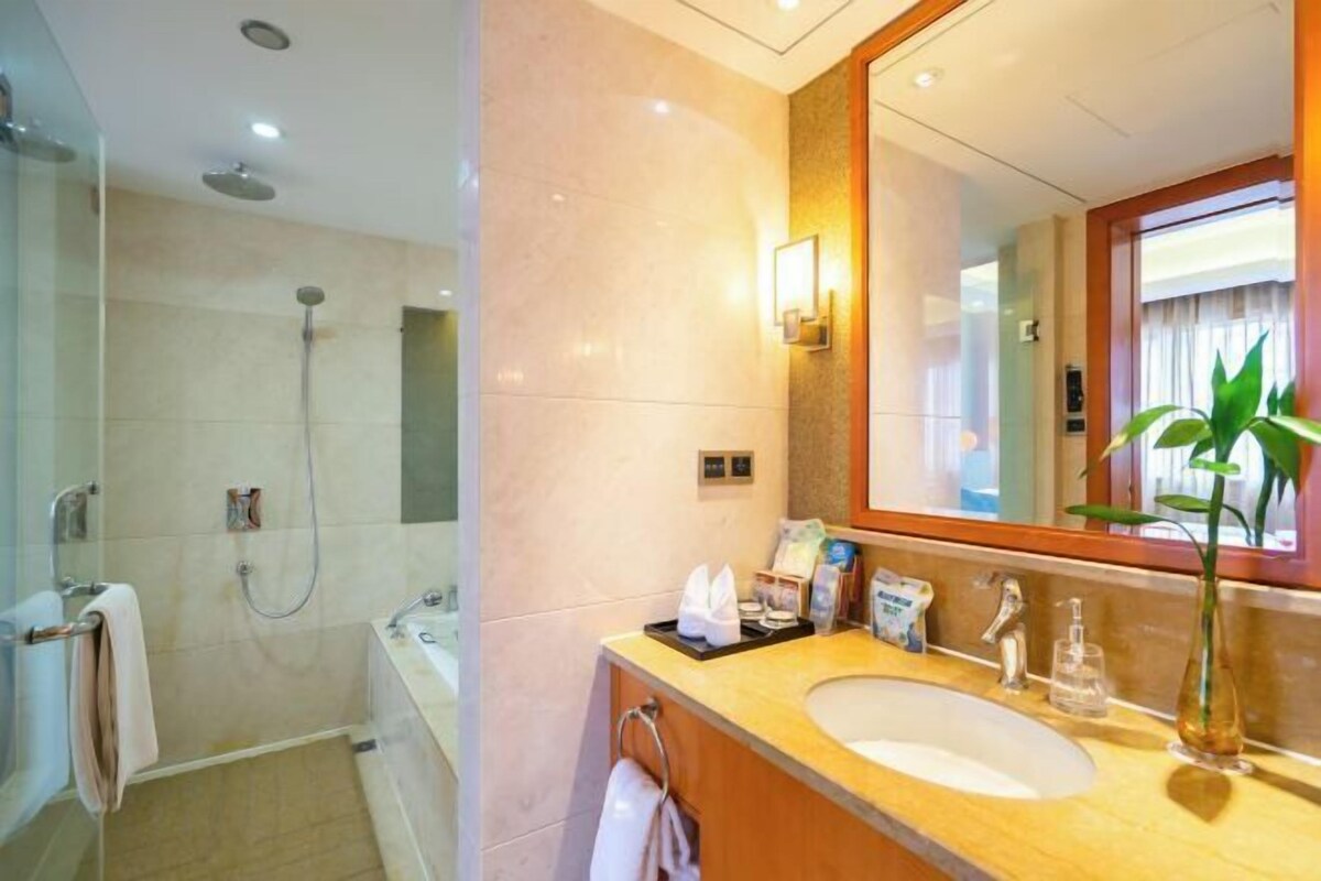 A modern bathroom with a large mirror, a sink, and a shower.
