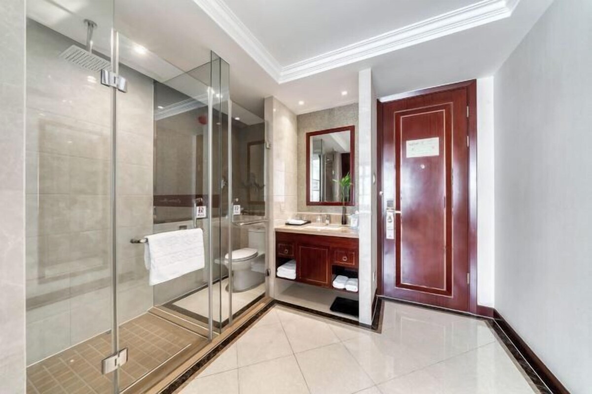 A modern bathroom with a glass-enclosed shower, a toilet, and a vanity with a mirror.