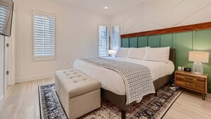 A bedroom with a bed, bedside table, lamp, and a bench.