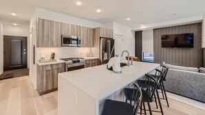 A modern kitchen with a central island, built-in appliances, and a dining area with bar stools.