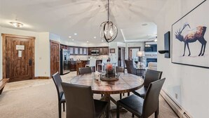A dining area with a round table, chairs, a chandelier, and a framed picture on the wall. - Best Mtn View-Ski In/Ski Out & Gondola to Downtown (Breckenridge)