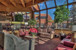 A spacious interior with large windows, a wooden ceiling, and multiple seating areas.