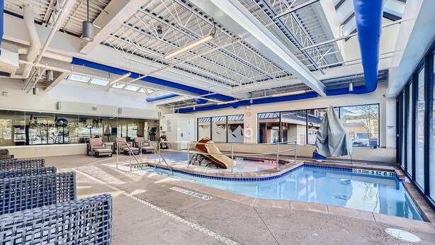 An indoor pool area with a slide, lounge chairs, and a view of the outside.