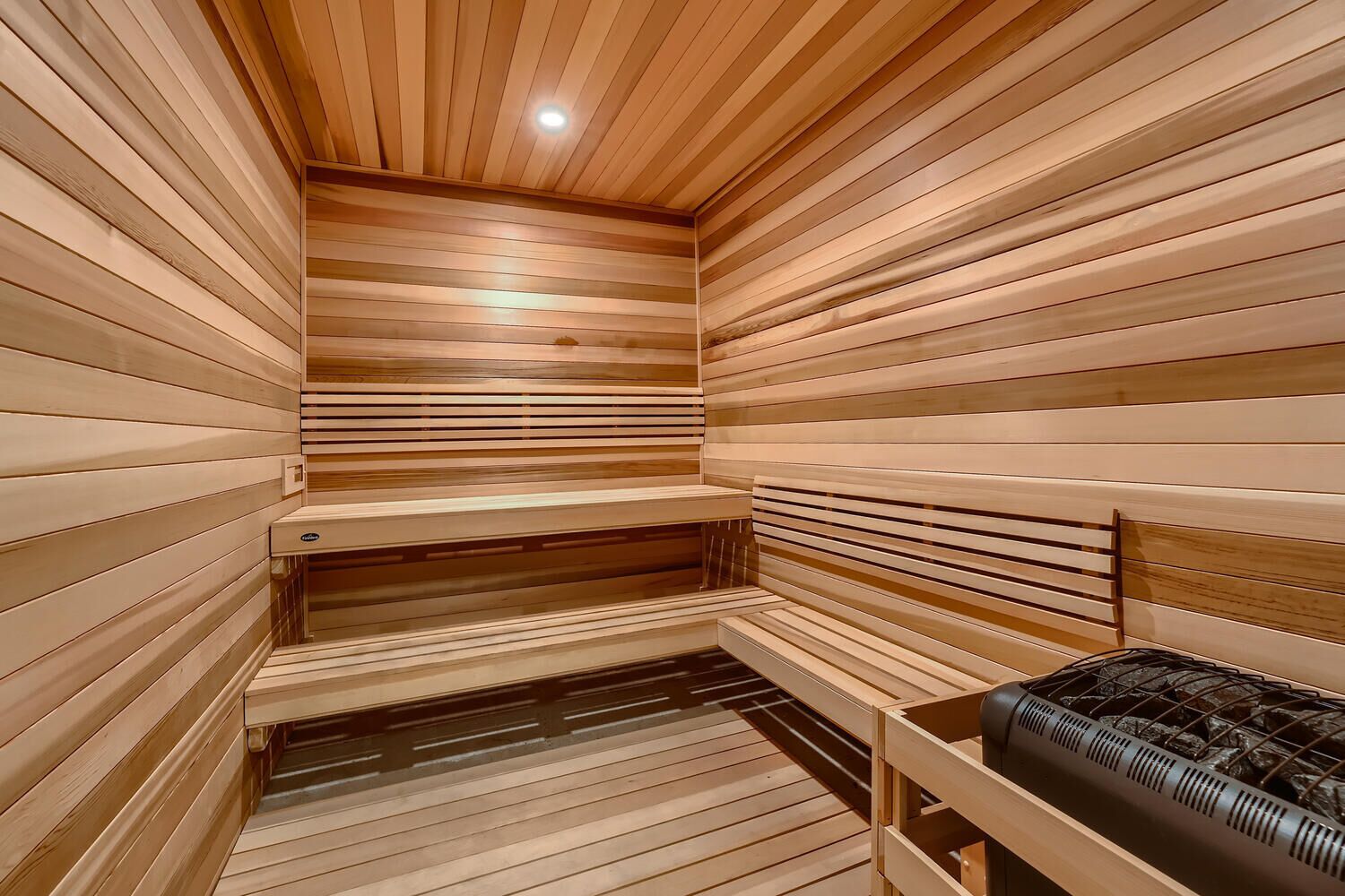 A sauna with wooden slats, benches, and a bench with a black towel.