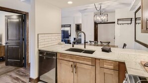 A modern kitchen with a large island, stainless steel appliances, and a pendant light.