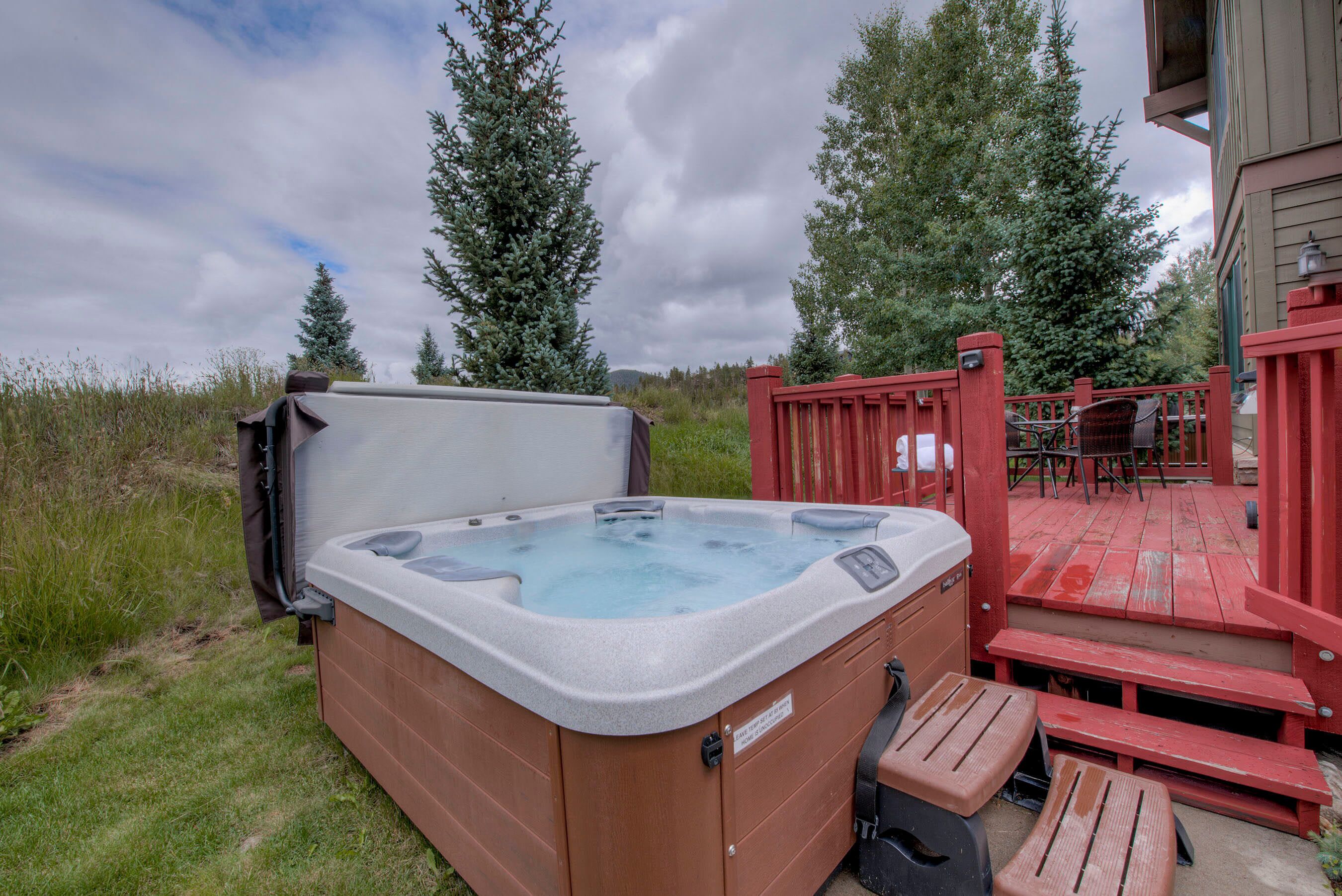 A hot tub in an outdoor setting with a wooden deck and a table and chairs nearby.