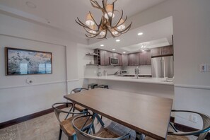 A modern kitchen with dark wood cabinets, stainless steel appliances, and a large dining table with chairs.