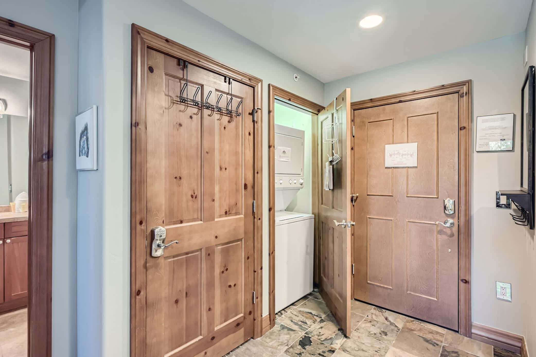 A hallway with wooden doors, a laundry machine, and a wall-mounted light fixture.