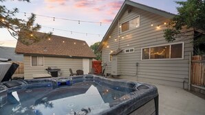 Un jardin avec un jacuzzi, des guirlandes lumineuses et une maison.
