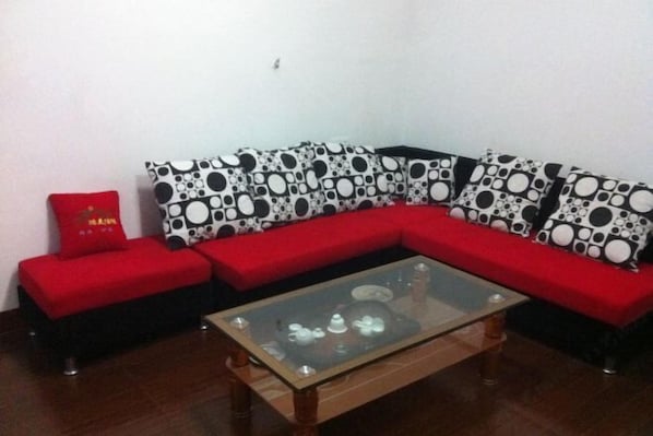 A living room with a red sofa, a glass coffee table, and patterned cushions. - Ninghua Jingtai Business Hotel (Ninghua)