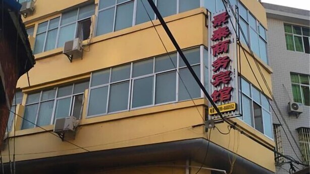 Un immeuble à plusieurs étages, doté d’une façade jaune et de grandes fenêtres.