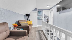 A modern living room with a sofa, a small table with a vase of flowers, and a lamp. - Quaint 2BR in Historical Little Italy
 (Cleveland)