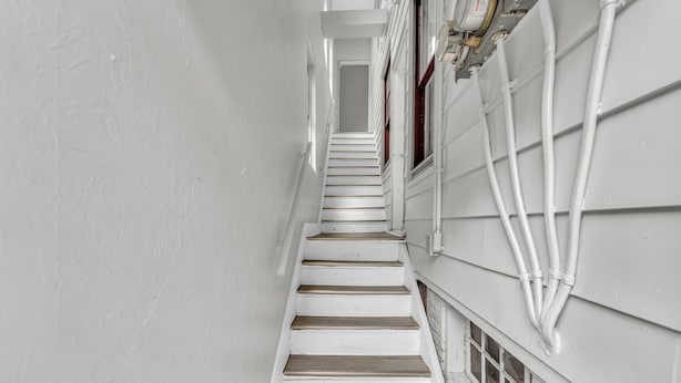 A narrow staircase with white walls and wooden steps leading upwards. - Quaint 2BR in Historical Little Italy
 (Cleveland)