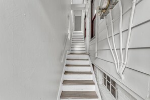 A narrow staircase with white walls and wooden steps leading upwards.