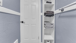 A bathroom with a white door, shelves with towels, and a towel rack. - Quaint 2BR in Historical Little Italy
 (Cleveland)
