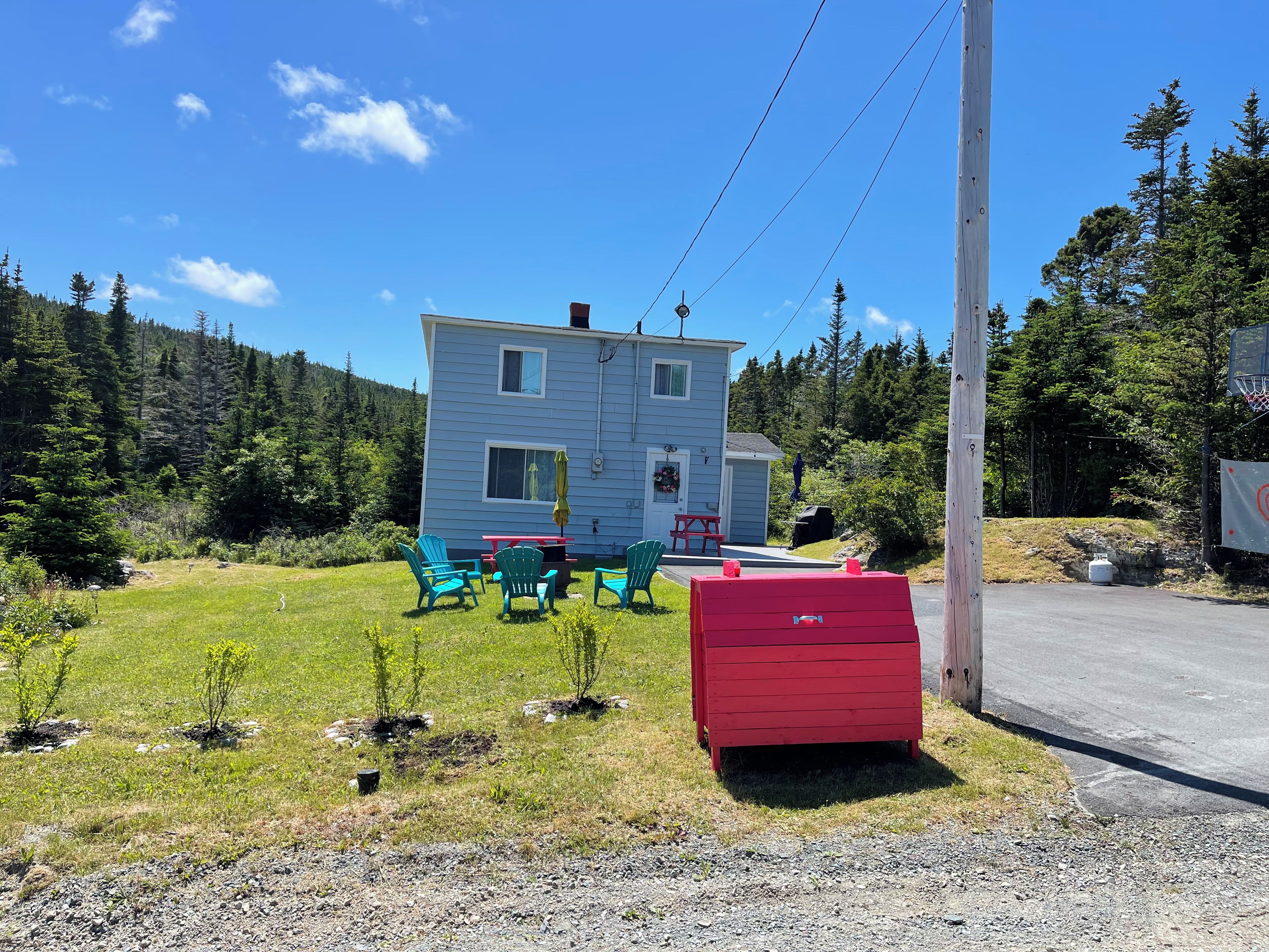 A two-story house with a front yard, outdoor seating, and a red shed.