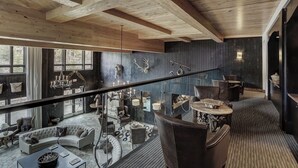 Un vaste espace de vie comprenant un canapé incurvé, une table basse et une cheminée. Un balcon avec une balustrade offre une vue sur l’intérieur.