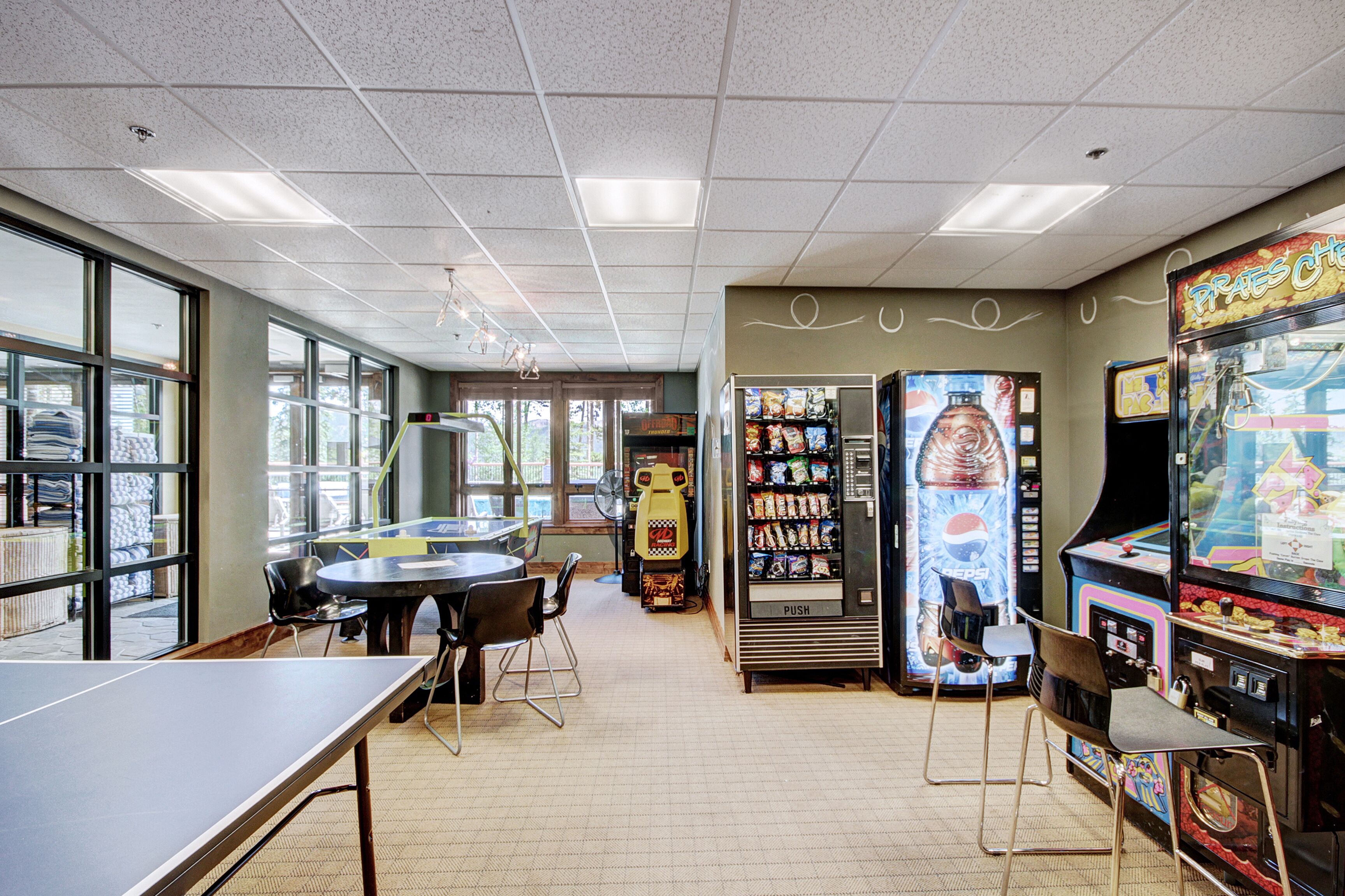 Une salle avec une table de ping-pong, des distributeurs automatiques et des jeux d’arcade.