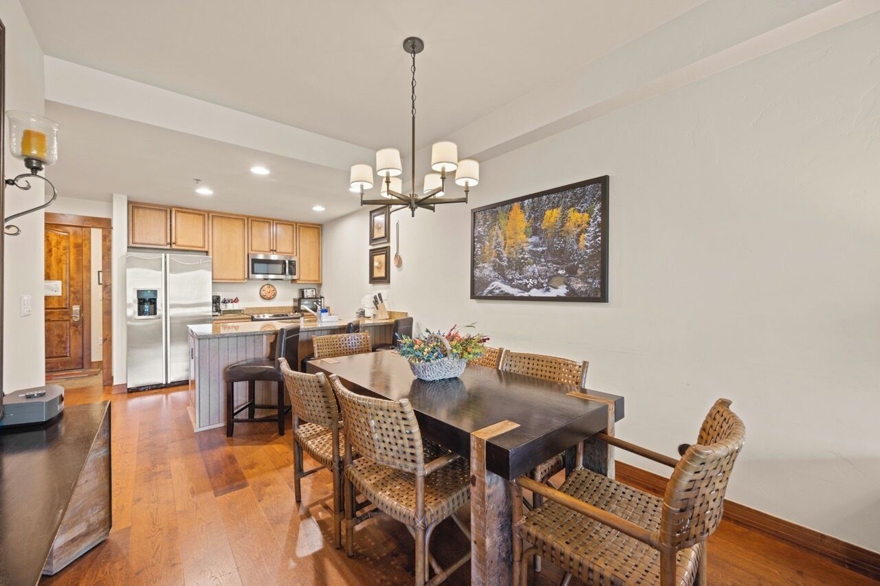 A dining area with a dark wooden table, wicker chairs, and a chandelier.