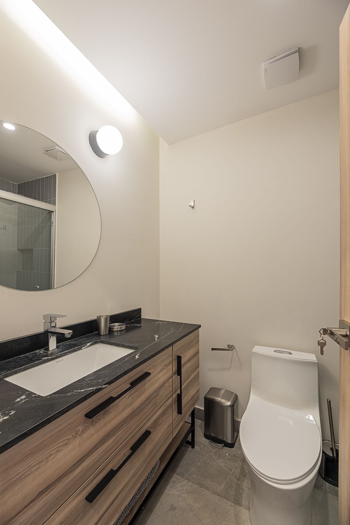 Un baño moderno con un espejo grande, un lavamanos y un inodoro.