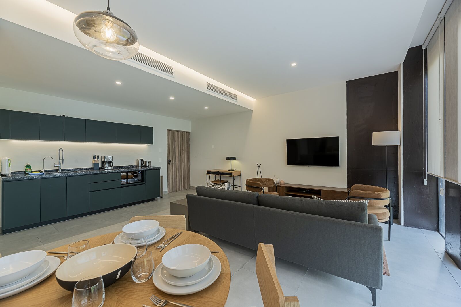 Un espacio habitable moderno con cocina, comedor y zona de estar con televisor.