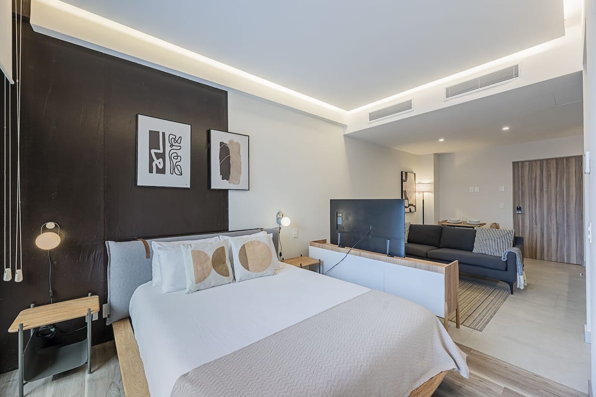 Una habitación de hotel moderna con una cama grande, un televisor, un sofá y una zona de comedor.