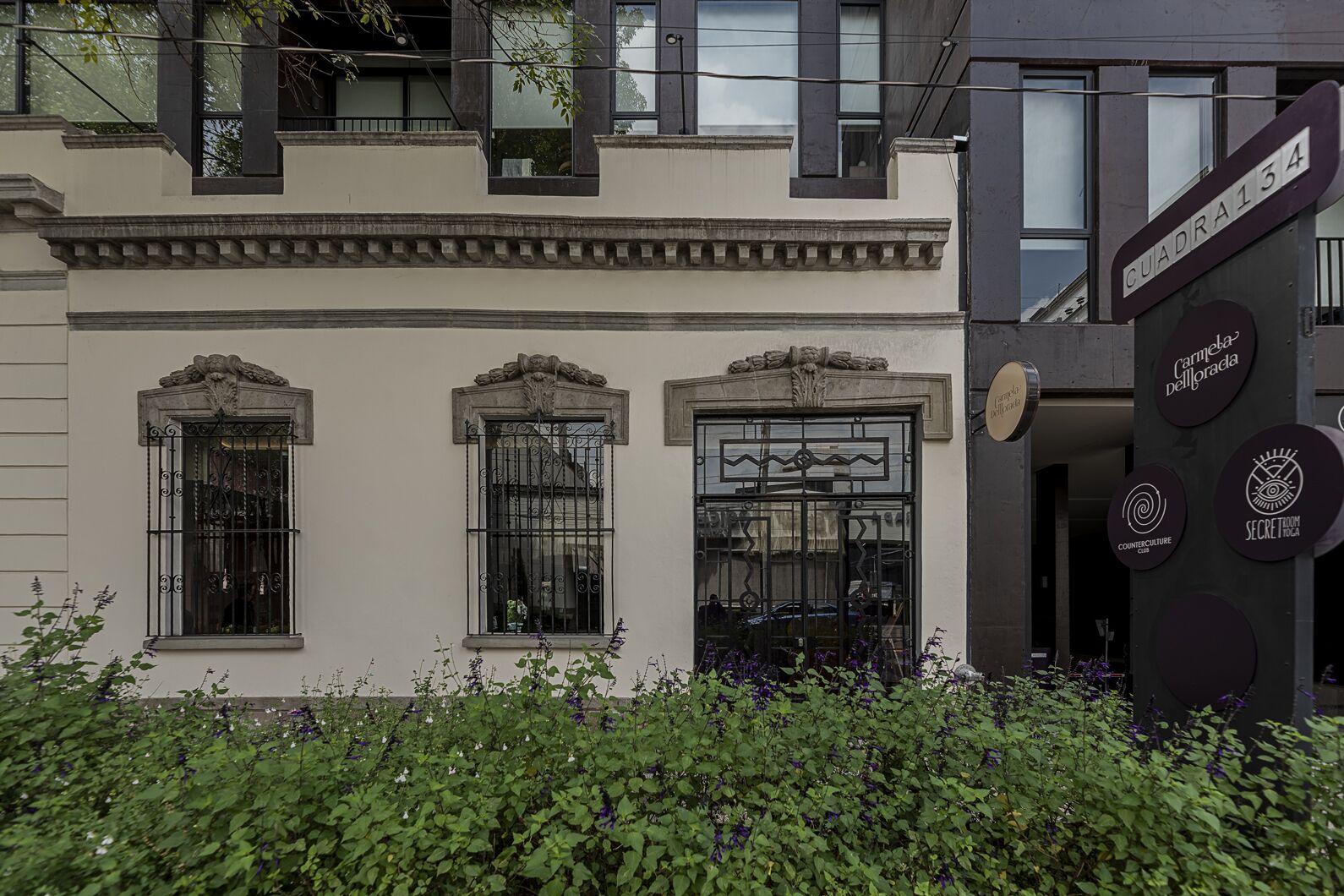 Um edifício com três janelas, cada uma adornada com grades de ferro decorativas e um elemento decorativo central sobre a porta.