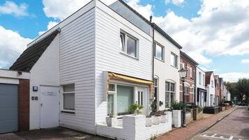 En toetages boligbygning med hvide facader, en lille forhave med plantekasser og en synlig garageport.