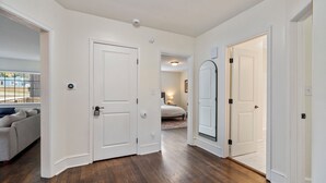 A hallway with a wooden floor, white walls, and a door leading to a bedroom. - Beautiful, Spacious 4 Bedroom Home one Block from High Point University (High Point)