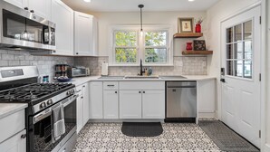 A modern kitchen with white cabinets, a stainless steel stove, and a dishwasher. - Beautiful, Spacious 4 Bedroom Home one Block from High Point University (High Point)