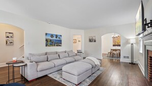 A modern living room with a grey sectional sofa, a small round table, and a fireplace. - Beautiful, Spacious 4 Bedroom Home one Block from High Point University (High Point)