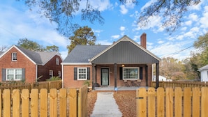 A residential house with a brick exterior, a front porch, and a wooden fence. - Beautiful, Spacious 4 Bedroom Home one Block from High Point University (High Point)