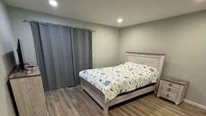 A bedroom with a bed, a dresser, a TV on a stand, and a nightstand. - Remodeled 3-bedroom condo in Marina walking distance to beach; STR25-000040 (Marina)