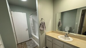 A bathroom with a shower, toilet, sink, and mirror. - Remodeled 3-bedroom condo in Marina walking distance to beach; STR25-000040 (Marina)
