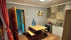 Eine kleine Küche mit Holztisch, Bank und Wasserspender.