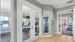 A hallway with glass doors leading to a fitness area and a children's play area.
