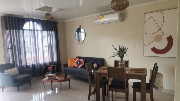 Ein Wohnzimmer mit Sofa, Sessel, Couchtisch und Esstisch mit Stühlen.