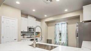 A modern kitchen with white cabinets, a stainless steel refrigerator, and a marble countertop. - Fresno House - BBQ, Fire Pit, 3 Bed, 2 Bath & 2 Car Garage! (Fresno)