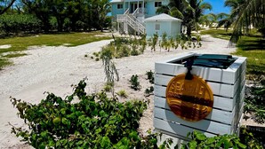Ein strandnahes Anwesen mit einem hellblauen Haus, einer Treppe, die zu einer Terrasse führt, und einem Schild mit der Aufschrift 'SEA SALT SEASALTGUINNESS.COM'.