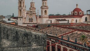 A historic church with two bell towers and a red dome, viewed from a rooftop terrace. - Hotel Boutique Pedregal (Coatepec)