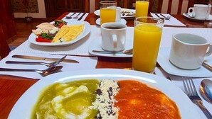 A dining table with a plate of food, a cup of coffee, and a glass of orange juice. - Hotel Boutique Pedregal (Coatepec)